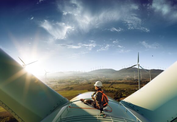 Wind farm worker sitting on top of a wind turbine